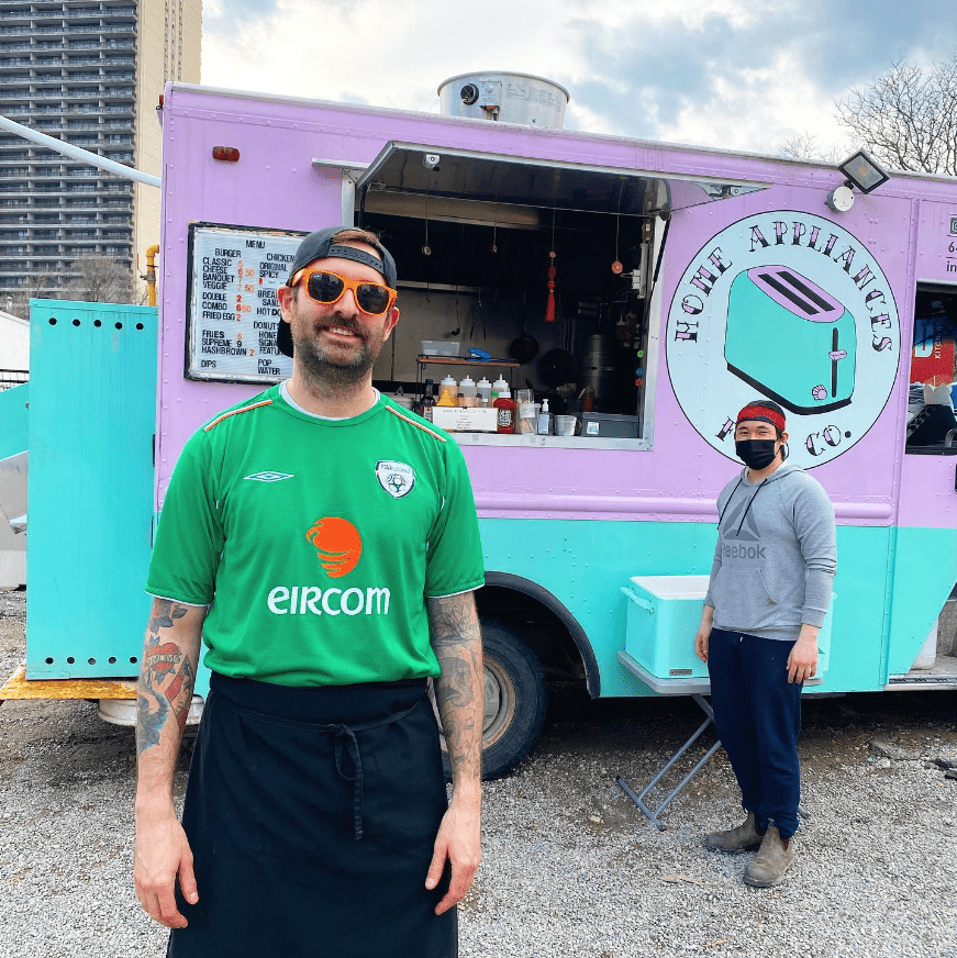pink and teal food truck with man wearing a green shirt and sunglasses in front of it operating a point of sale and mobile ordering system