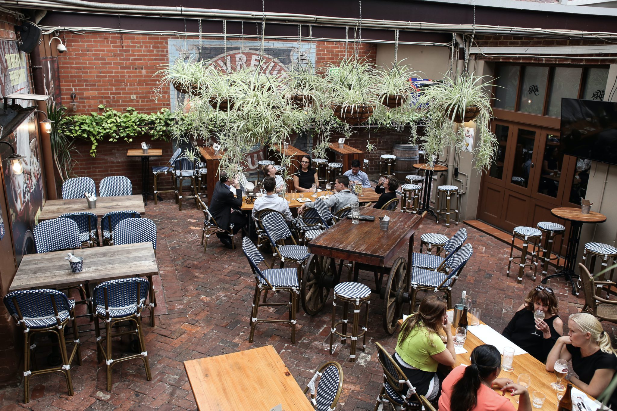 a small restaurant patio view from above. Tables and chairs, and hanging greenery